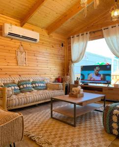 uma sala de estar com um sofá e uma televisão em شاليهات الأكواخ الثلاثة em Khalij Salman