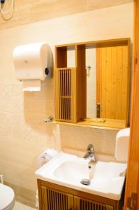 ein Badezimmer mit einem Waschbecken, einem Spiegel und einem WC in der Unterkunft شاليهات الأكواخ الثلاثة in Khalij Salman