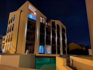 a building with a pool in front of it at night at Fides Stylish Apartments Tivat with Pool in Tivat
