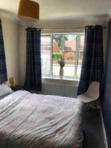 1 dormitorio con cama, ventana y silla en Stonyhurst, en Chorley