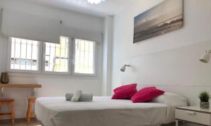 una camera bianca con 2 letti con cuscini rossi di Green Beach Las Canteras a Las Palmas de Gran Canaria
