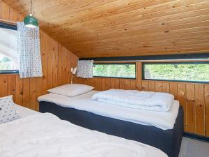two beds in a room with wood walls and windows at Holiday home Sydals LXXXIX in Neder Lysabild