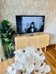 ein Wohnzimmer mit einem TV und weißen Blumen in der Unterkunft Auszeit Niedersfeld in Winterberg