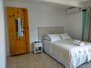 a bedroom with a white bed and a small table at Itacaré Flats in Itacaré