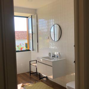 a white bathroom with a sink and a mirror at Solar Nossa Senhora da Conceição in Capelas