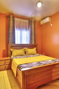 1 dormitorio con 1 cama con sábanas amarillas y ventana en Meuble Modon Nyalla, en Douala