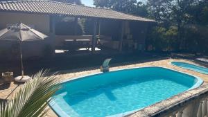 een zwembad in een tuin met een tafel en een parasol bij Chacara recanto da paz in Mairinque