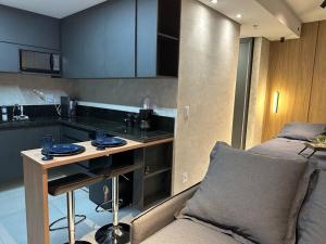 a kitchen with a table and a couch in a room at Studio Aconchegante e Completo in Ribeirão Preto