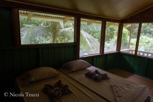 a bedroom with a bed with two pillows and windows at Complejo Ecoturistico Tamandua in Drake