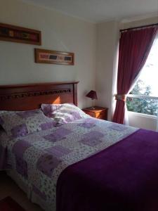 a bedroom with a purple bed and a window at Bahia Pelícanos Horcón depto. en primera línea in Puchuncaví
