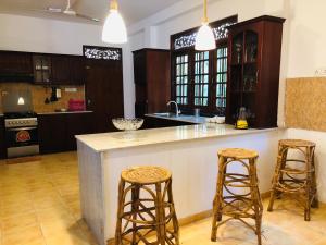 eine Küche mit einer großen Insel mit zwei Barhockern in der Unterkunft Hikka Villa in Hikkaduwa