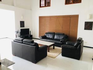 ein Wohnzimmer mit schwarzen Ledermöbeln und einem Tisch in der Unterkunft Hikka Villa in Hikkaduwa