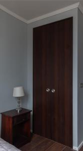 1 dormitorio con armario de madera y mesa con lámpara en Habitaciones en Departamento compartido centro de Viña, en Viña del Mar