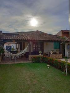 a house with a hammock in the front yard at Casa da Lua in São Pedro da Aldeia