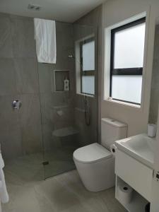 a bathroom with a shower and a toilet and a sink at Paradise In Whitianga B & B in Whitianga