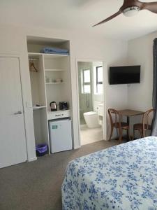 a bedroom with a bed and a table and a television at Paradise In Whitianga B & B in Whitianga