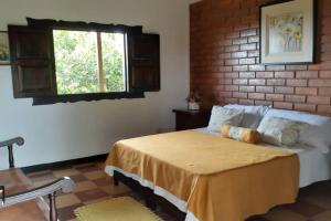 Un dormitorio con una cama con una pared de ladrillos. en Finca cafetera para tu descanso-Finlandia Quindio, en Filandia