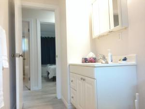 a white bathroom with a sink and a mirror at Sweethome - 10 min to Rogers Place & so much more in Edmonton