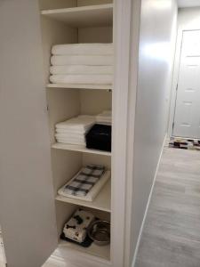 ein Schrank mit weißen Handtüchern und gefalteten Handtüchern in der Unterkunft Sweethome - 10 min to Rogers Place & so much more in Edmonton