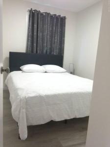 uma cama com lençóis brancos e almofadas num quarto em Sweethome - 10 min to Rogers Place & so much more em Edmonton