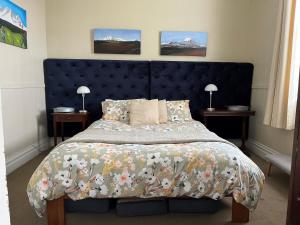 a bedroom with a large bed with a blue headboard at Kosbys Cottage, Tongariro 
