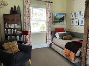 a bedroom with a bed and a chair and a window at Kosbys Cottage, Tongariro 