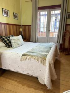 a bedroom with a bed with a blanket on it at Hostal Florencia in Puerto Varas