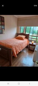 a bedroom with a bed with an orange comforter at Lorena in Concepción