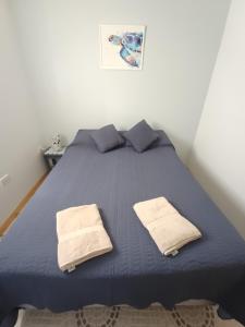 1 dormitorio con 1 cama azul y 2 toallas en Departamento Las Maras III en El Chaltén