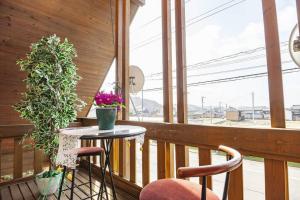 - un balcon avec 2 chaises et une table fleurie dans l'établissement Log house Tomi-chan's house / Private building, à Echizen