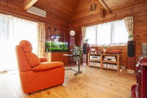un salon avec une chaise orange et une télévision dans l'établissement Log house Tomi-chan's house / Private building, à Echizen