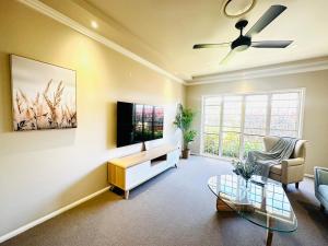 a living room with a couch and a tv at Luxury Holiday Home in Middle Ridge Toowoomba in Harristown