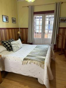 Un dormitorio con una cama con una manta. en Hostal Florencia, en Puerto Varas
