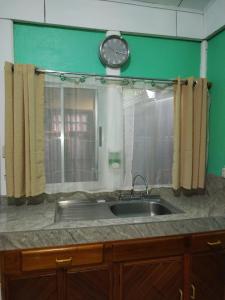 a kitchen sink with a clock on a mirror at Villa Gabriela, Casa Tucan in Liberia