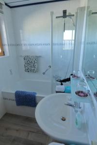 a white bathroom with a sink and a bath tub at Ferienhaus Haas in Ruhpolding