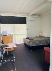 Zimmer mit einem Bett, einem Schreibtisch und einem Tisch in der Unterkunft Rubicon Hotel Motel in Eildon