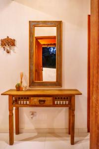 a wooden table with a mirror on a wall at Pousada Casa Joana Trancoso in Trancoso