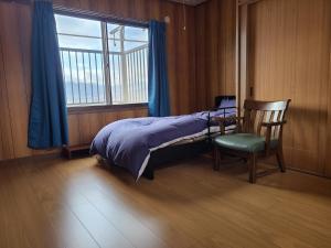 a bedroom with a bed and a chair and a window at Guesthouse Hidamari no Yado - Vacation STAY 04353v in Tomi