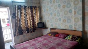 a small bedroom with a bed and a tv at Sea pebbles in Digha
