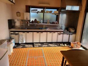 una cucina con armadi bianchi e pavimento arancione di Guesthouse Hidamari no Yado - Vacation STAY 04353v a Tomi