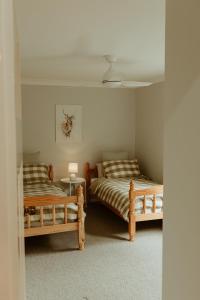una camera con due letti e un tavolo con una lampada di Linden Cottage Farm Stay a Harden