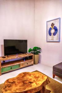 a living room with a wooden table and a flat screen tv at Pousada Casa Joana Trancoso in Trancoso