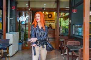 una mujer con el pelo rojo de pie con una maleta en Konur Hotel, en Ankara