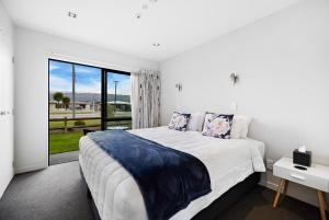 a white bedroom with a large bed and a window at Avenue Motel in Alexandra