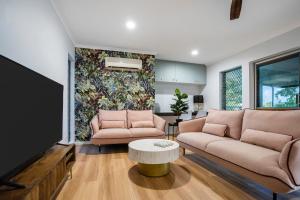 East TrinityにあるDeco View Family Oasis in Cairnsのソファ2つとテレビのあるリビングルーム