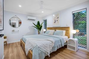 Deco View Family Oasis in Cairns في East Trinity: غرفة نوم بيضاء مع سرير ومرآة