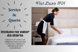 una mujer haciendo una cama en una habitación de hotel en FLAT LUXO PREMIUM - Londrina Flat Hotel - 43m² #garagemgrátis, en Londrina