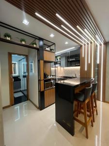 una cocina con encimera negra y algunas sillas en FLAT LUXO PREMIUM - Londrina Flat Hotel - 43m² #garagemgrátis, en Londrina