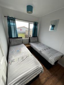 two beds in a small room with a window at Captivating 2-Bed chalet in Bessingby