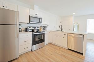 una cocina con armarios blancos y electrodomésticos de acero inoxidable en Idyllic & Cozy Stylish Belmont Haven near Lewiston - 1BR 1BA Apartment, en Auburn